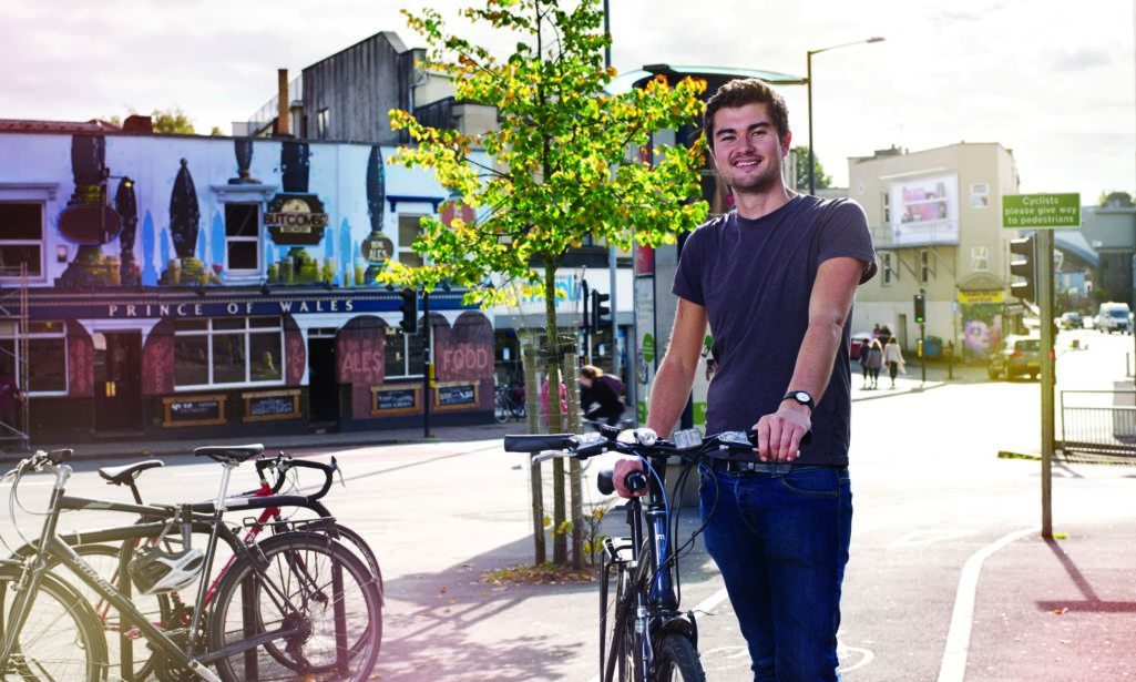 Young man standing with his bike on Gloucester Road Bristol