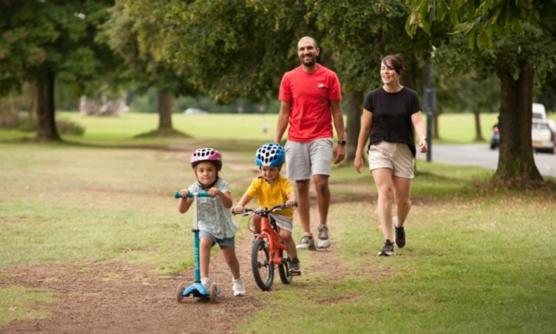 Family walking and cycling along the Down park in Bristol