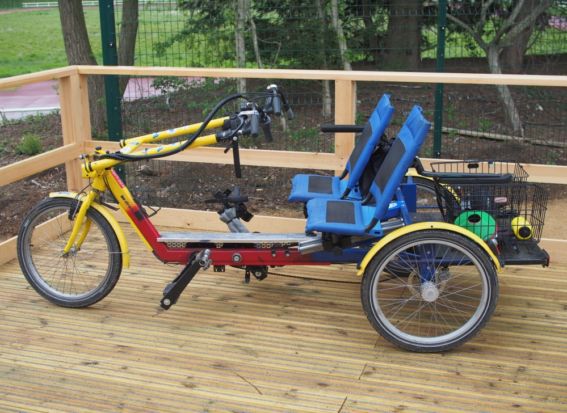 A yellow and red adult size side-by-side tandem on a wooden platform