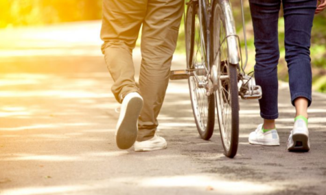 Stock image of man walking along with bicycle