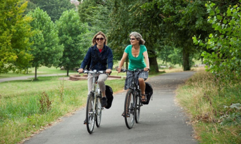 Two women cycling through a Bristol park