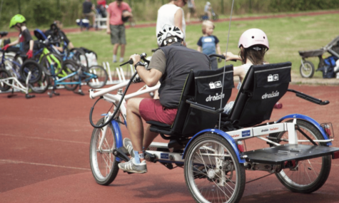 Two people riding an adapted bike around cycle track